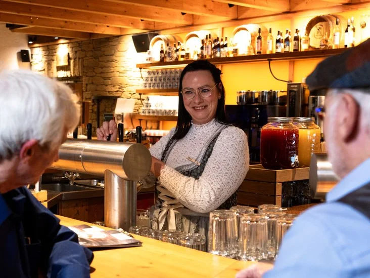 Gäste an der Bar einer Bavaria Alm