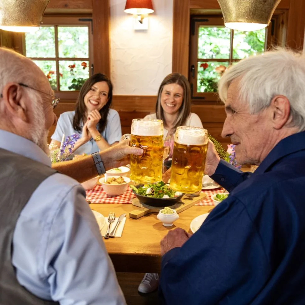 Gäste einer Bavaria Alm stoßen mit gezapften Bier an