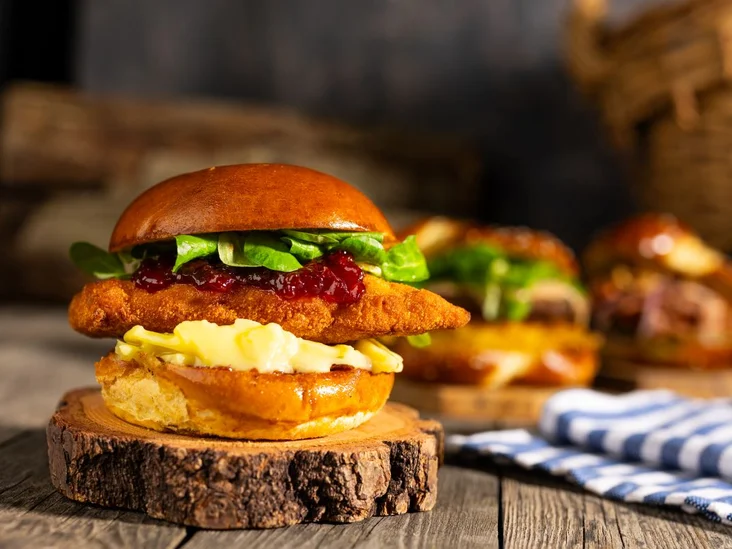 Der Crispy Hendl-Burger der Bavaria Alm auf einem Holztisch.