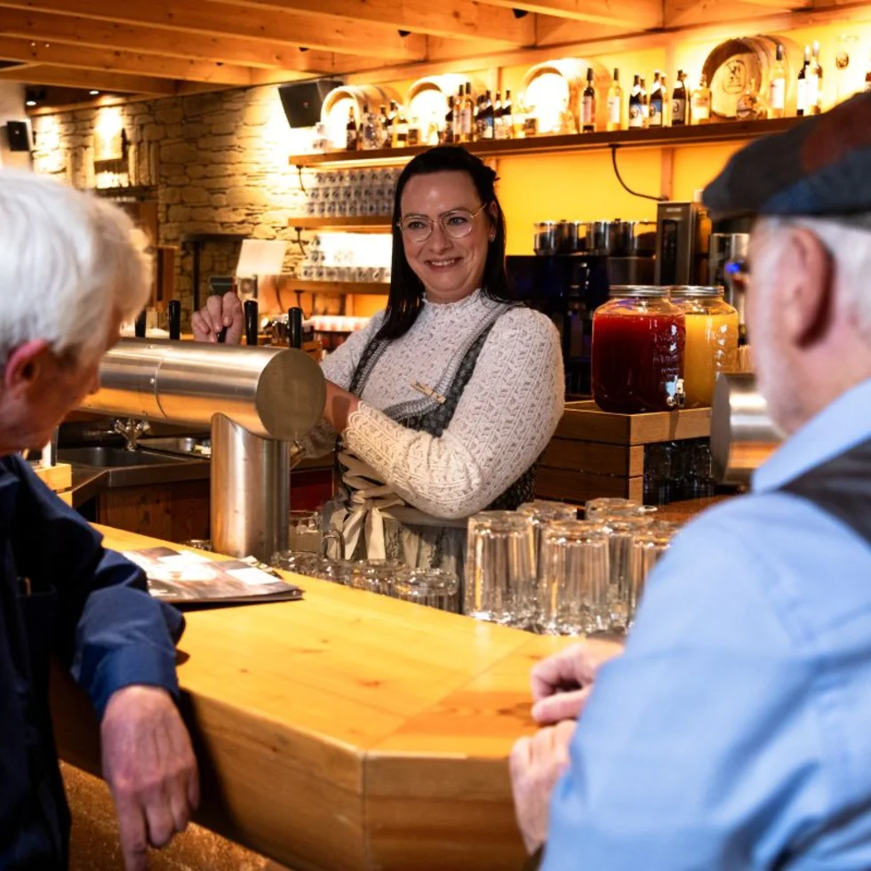 Gäste an der Bar einer Bavaria Alm